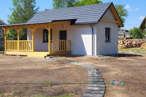 Domek modułowy z tarasem – realizacja Perfect Cube w woj. lubuskim, jasna elewacja, grafitowy dach, nowoczesna bryła i przygotowany teren wokół budynku Domek modułowy z tarasem – realizacja Perfect Cube w woj. lubuskim, jasna elewacja, grafitowy dach, nowoczesna bryła i przygotowany teren wokół budynku