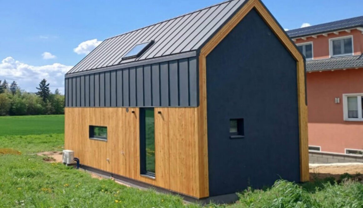 Nowoczesny dom modułowy Perfect Cube w Swisttal w Niemczech z elewacją drewnianą i grafitową blachą na rąbek w minimalistycznym stylu nowoczesnej stodoły.