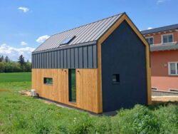 Nowoczesny dom modułowy Perfect Cube w Swisttal w Niemczech z elewacją drewnianą i grafitową blachą na rąbek w minimalistycznym stylu nowoczesnej stodoły.